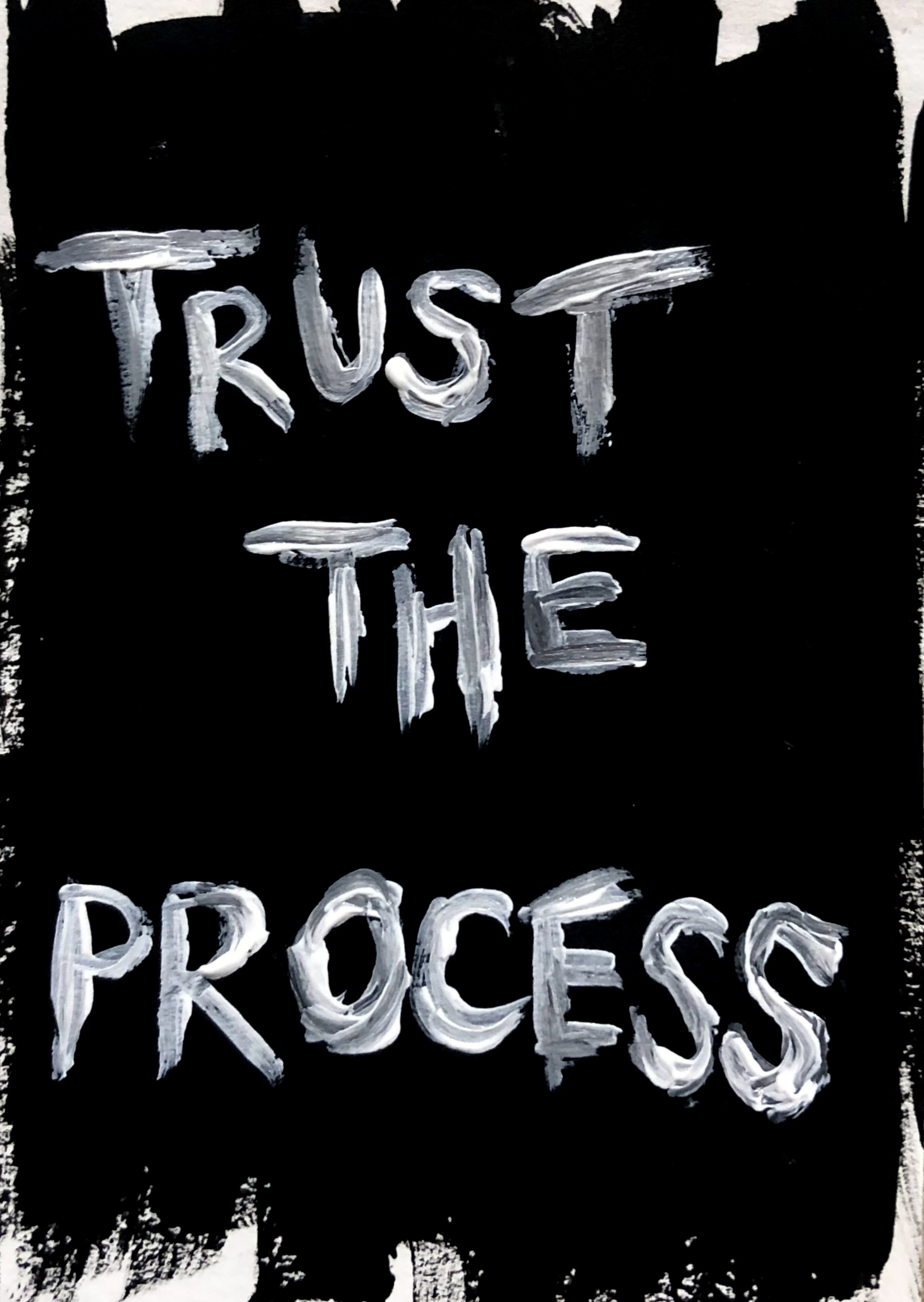 An art journal page with the words trust the process in white paint against a messy black background.