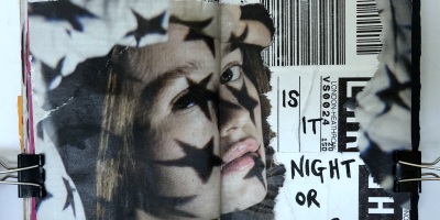 A field notes art journal with ephemera and the words "is it night or day?"; the page was created with ink and collage material.