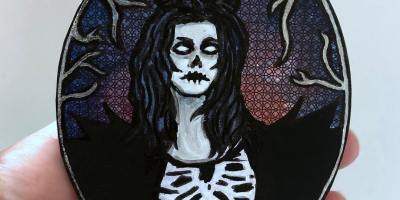 Coaster art of a skeletal horned demon woman; it was created with ink, collage materials, and acrylic paint.