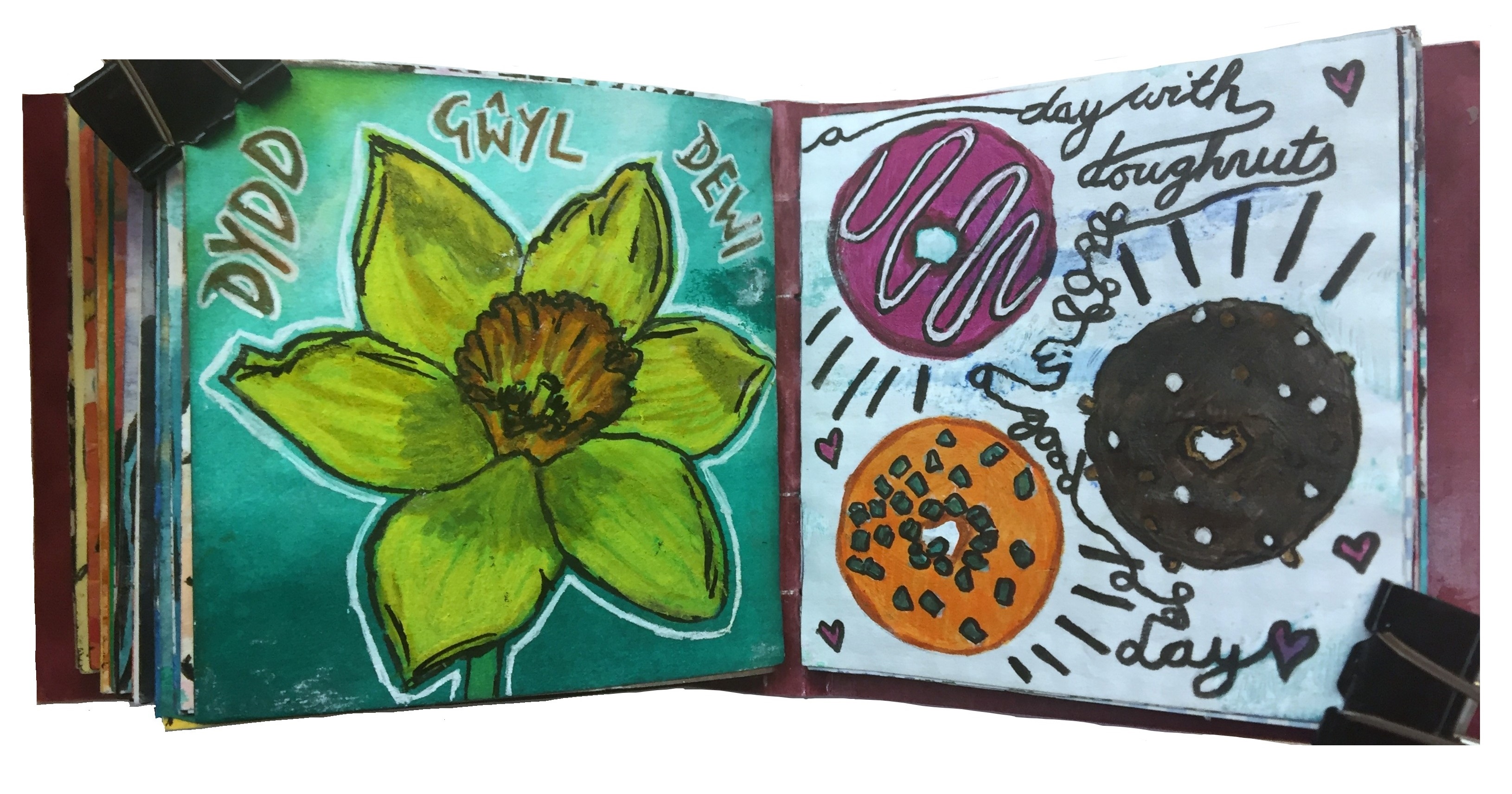 Days 60 and 61/365 of Year of Creative Habits. A mixed media art journal illustration of a daffodil with the words dydd gwyl dewi surrounding it for St. David's day and a doodle of doughnuts and the words a day with doughnuts is a good day.